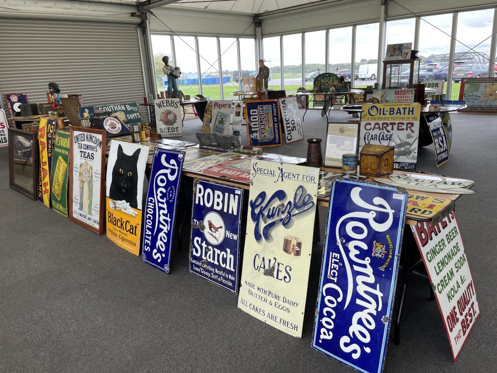 Rows of vintage enamel advertising signs lined up on viewing tables before the sale
